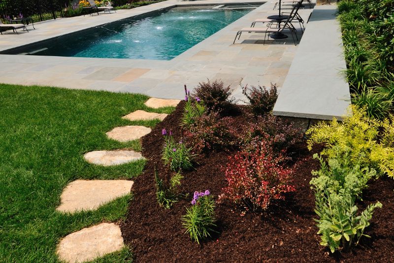Landscaped garden bed with stepping stones beside a paved pool area, Rockhampton